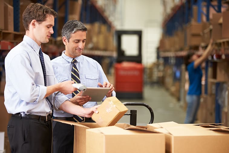 Image of two professionals standing over some boxes in a warehouse