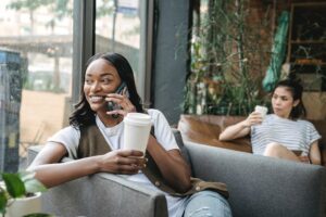 Woman sitting in coffee shop holding a cell phone.