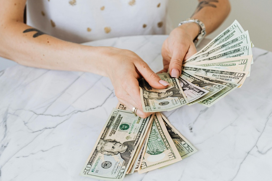 Woman counting cash at a table.