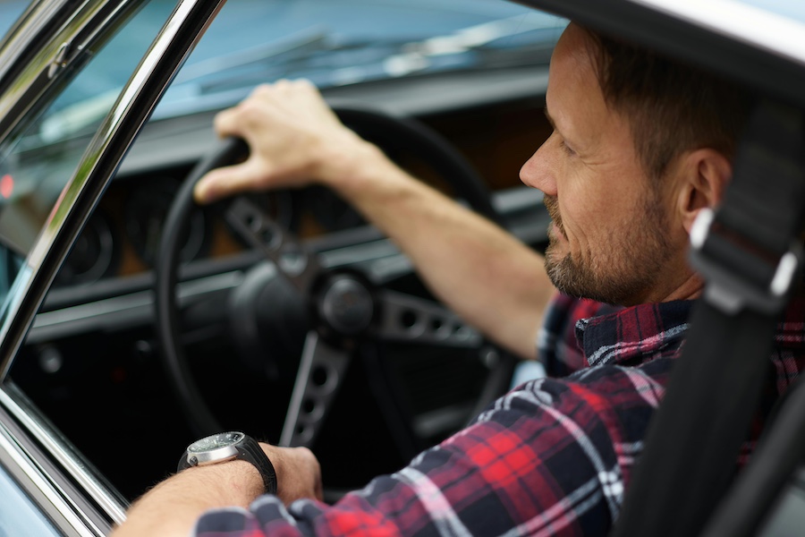 Man in flannel driving a car.