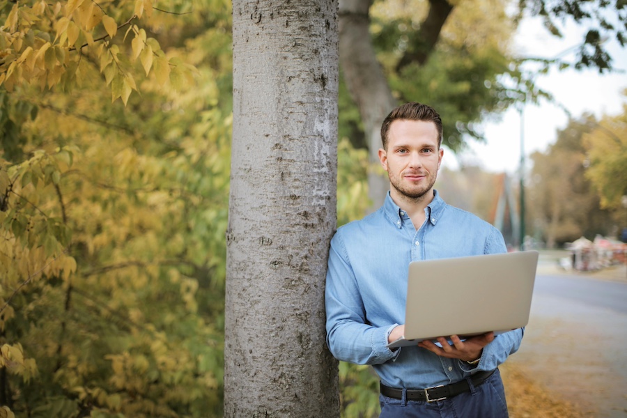 Man standing against a tree with changing leaves.