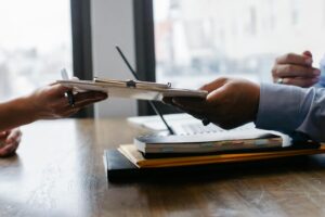 An office worker handing paperwork to another person.