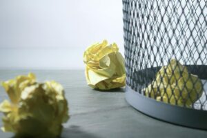 Wastebasket with crumpled up papers.