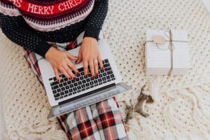 Woman in holiday clothes typing on her laptop.