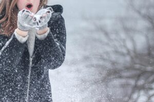 Woman blowing snow from her hands.