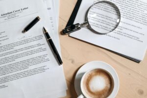 Work space with papers, coffee, pen, and magnifying glass.