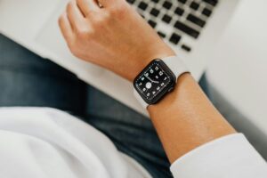 Office worker at laptop looking at their watch.