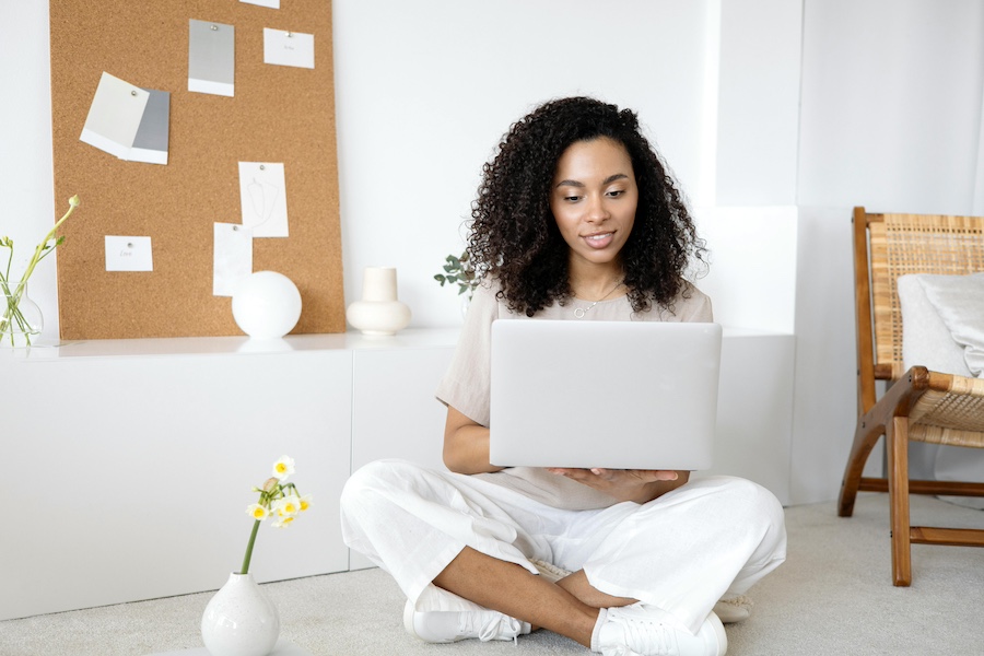 Woman sitting on floor looking at a laptop.