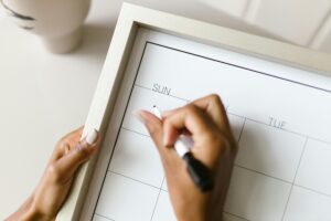 A hand using a marker to add information to a calendar.