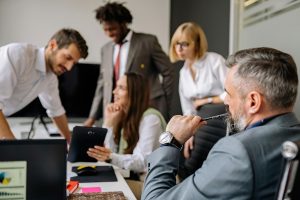 Manager watching his busy team work at a conference table.