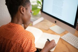 Woman at computer with a notebook, brushing up on skills in a cooling job market.