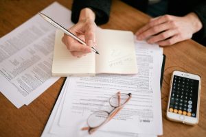 Hands taking notes as a woman prepares her taxes.