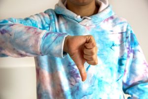 Young man in a colorful sweatshirt giving a thumbs down.