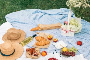 A summer picnic scene with sun hats, flowers, bread, berries, and more.