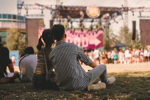 Two people sitting on a lawn enjoying summer entertainment.