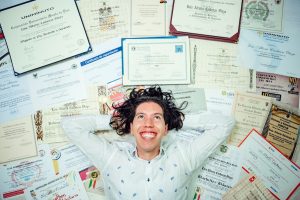Smiling worker with an array of certifications and degrees behind them.