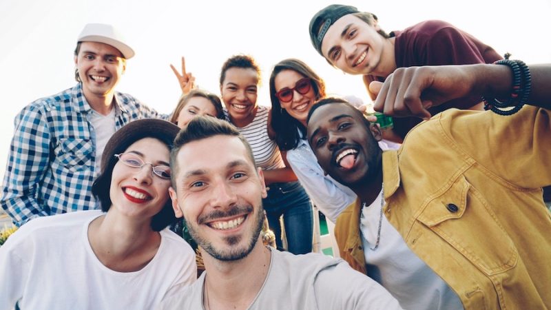 A group of friends, outside, smiling for the camera.