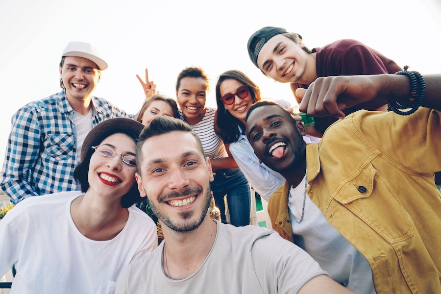 A group of friends, outside, smiling for the camera.